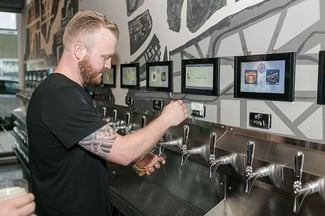 man pouring his own beer at an iPourit self serve draft system